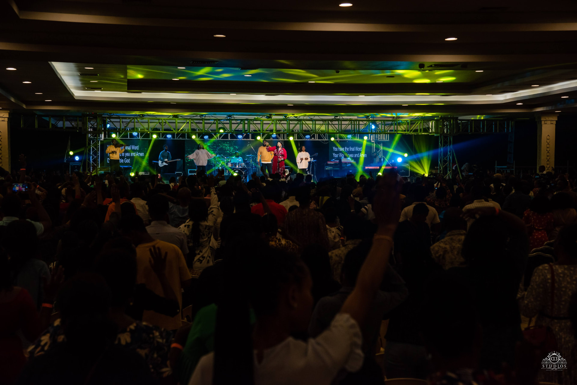 A worship leader singing at a microphone in warm stage light